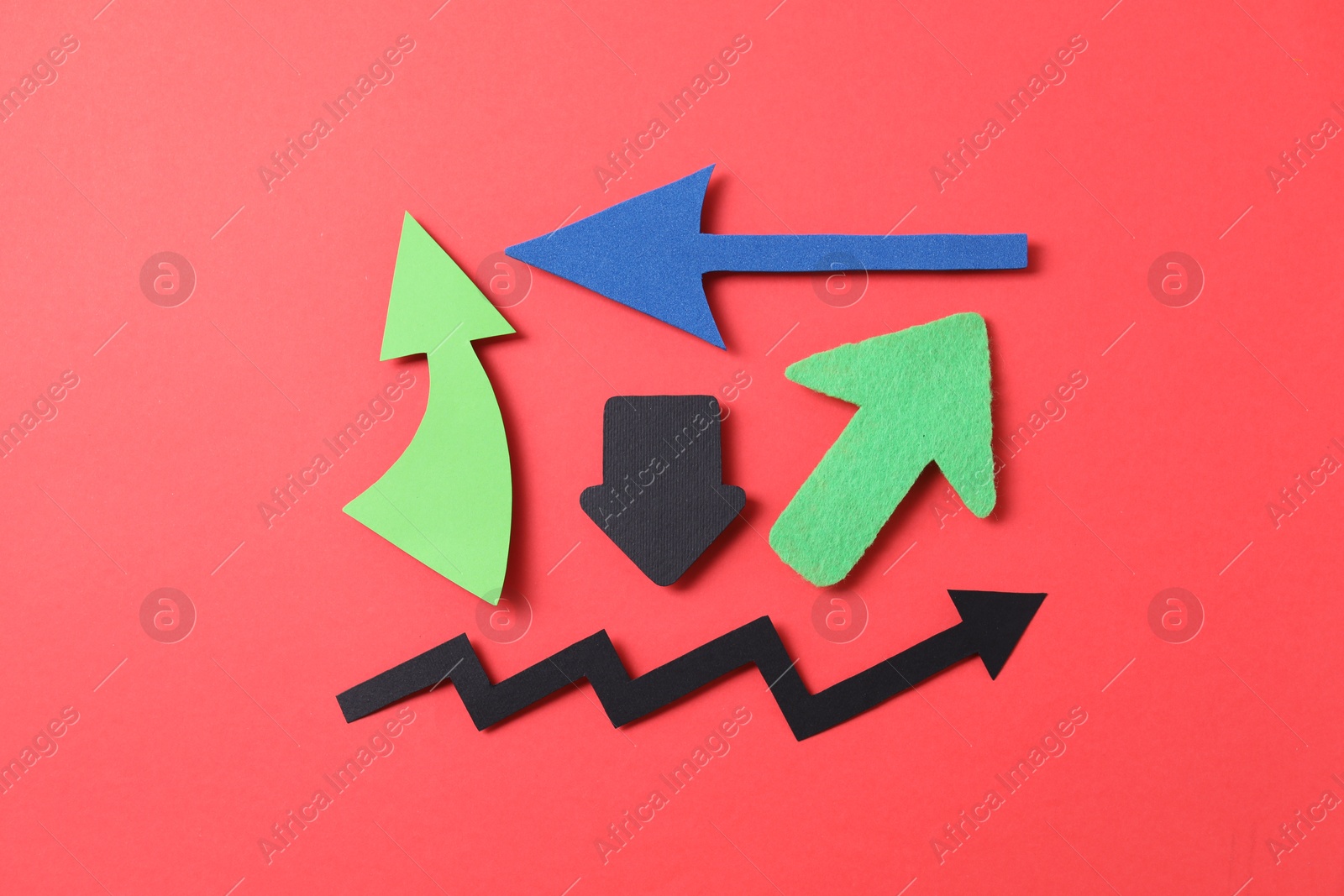 Photo of Different paper arrows on red background, flat lay