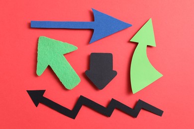 Photo of Different paper arrows on red background, flat lay