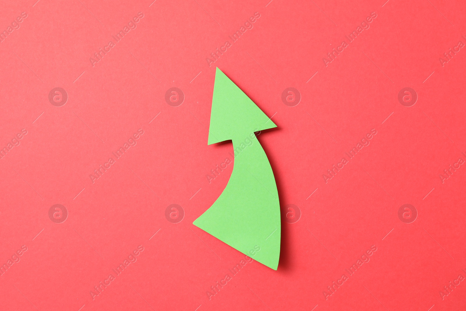 Photo of One green paper arrow on red background, top view