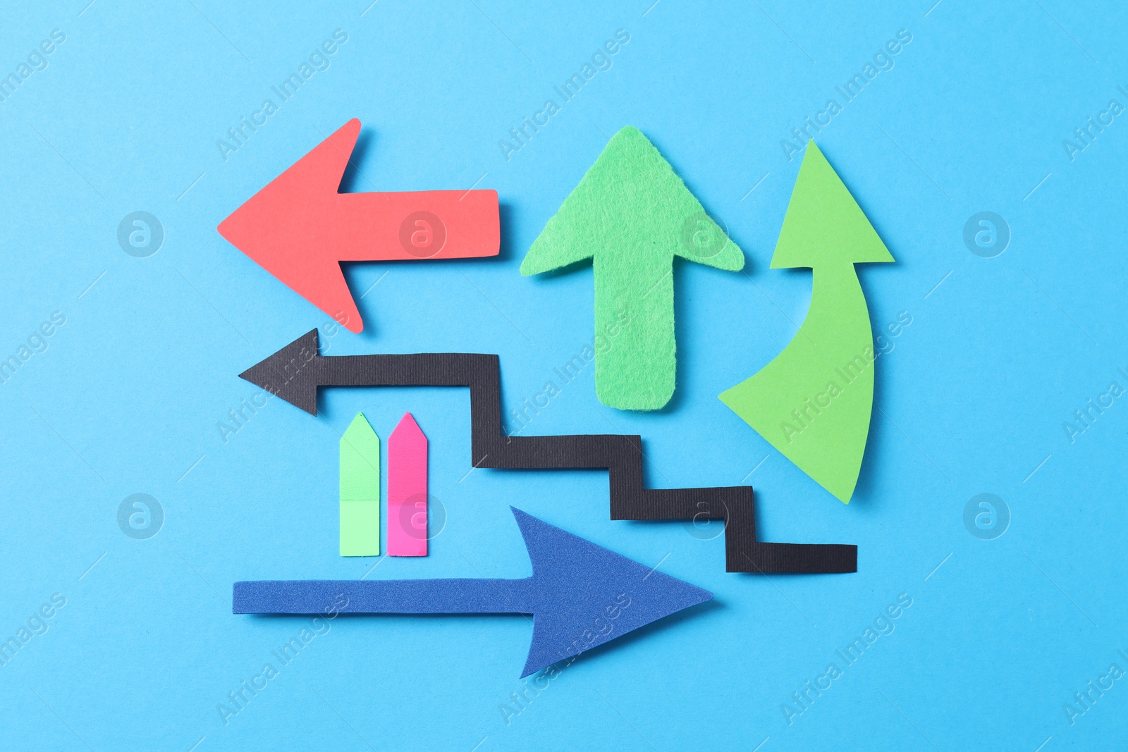 Photo of Different paper arrows on light blue background, flat lay