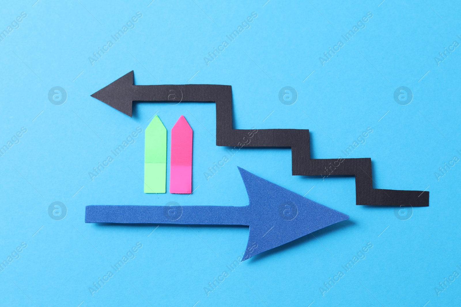 Photo of Different paper arrows on light blue background, flat lay