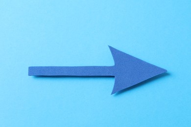 Photo of One foam paper arrow on light blue background, top view