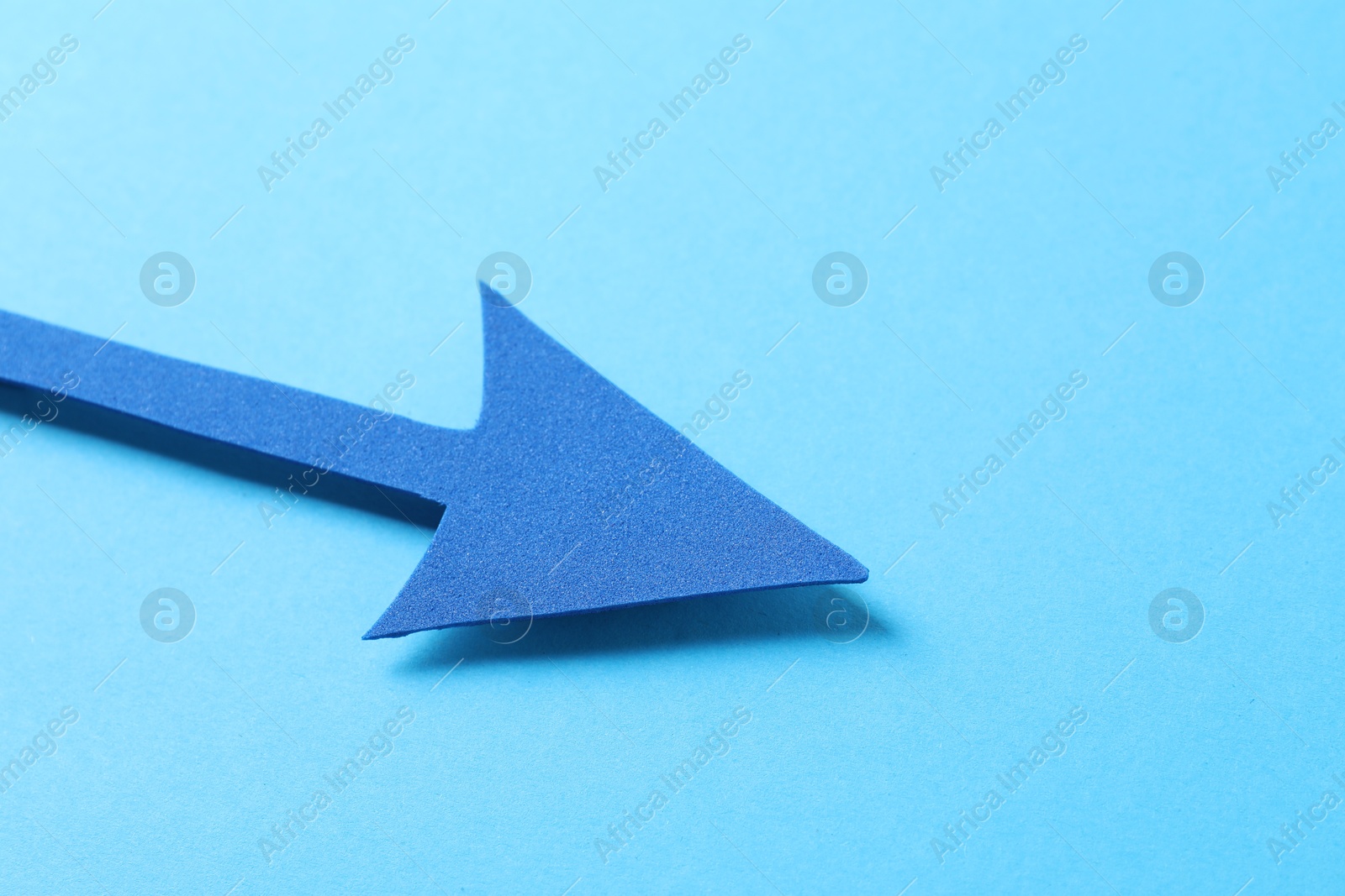 Photo of One foam paper arrow on light blue background, closeup