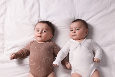 Photo of Cute twin babies resting on bed indoors, top view