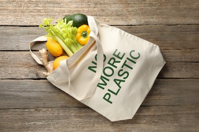 Image of Eco bag with No More Plastic text and products on wooden background, top view