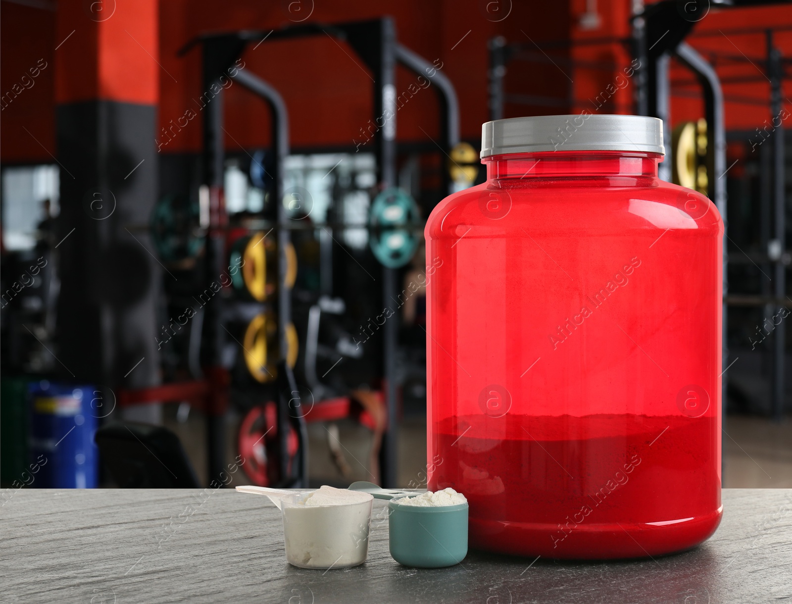 Image of Protein powder on grey table in gym, space for text