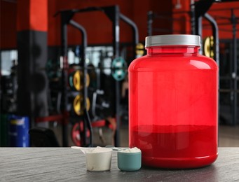 Image of Protein powder on grey table in gym, space for text