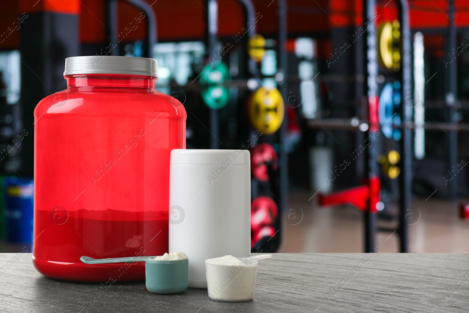 Image of Protein powder on grey table in gym, space for text