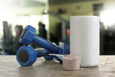 Protein powder and dumbbells on table in gym