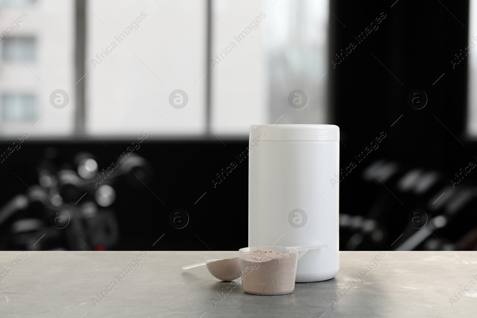 Image of Protein powder on grey table in gym, space for text