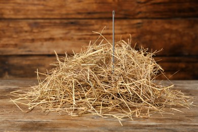 Sewing needle in haystack on wooden background, closeup view