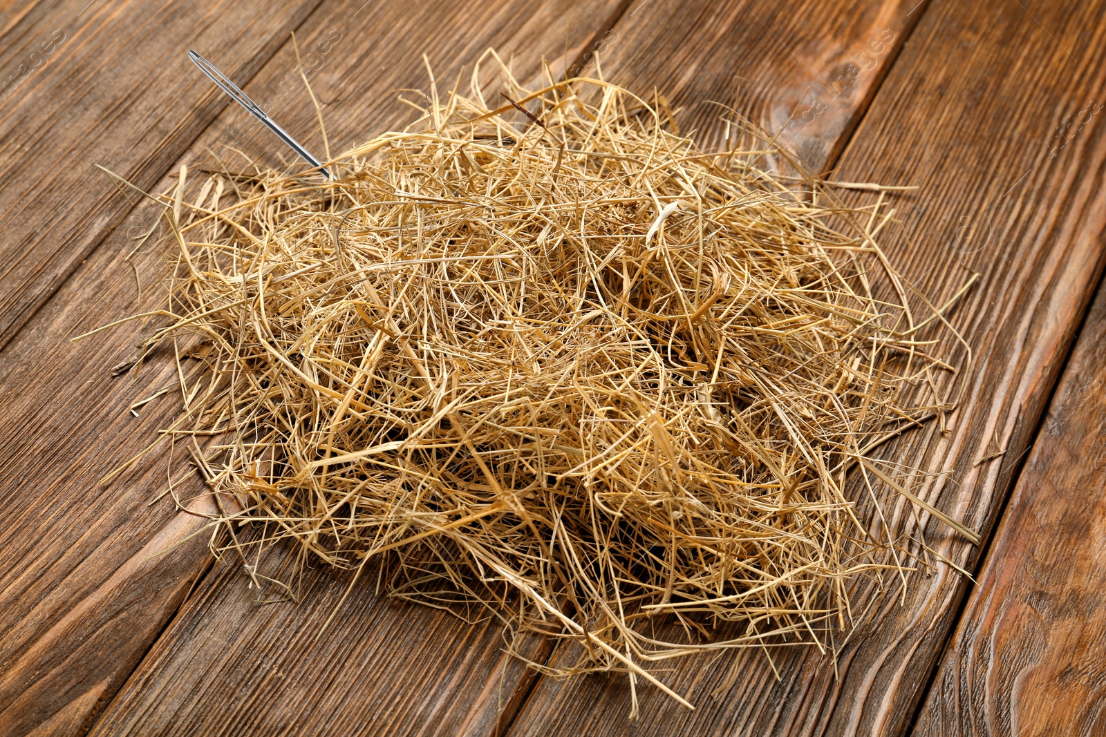 Image of Sewing needle in haystack on wooden background, closeup view