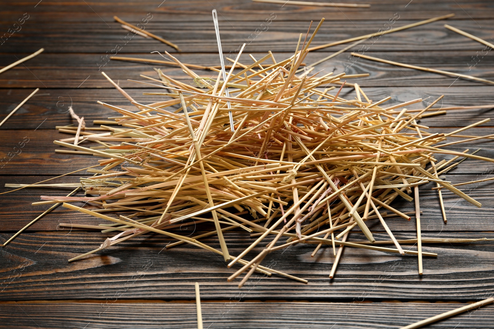 Image of Sewing needle in haystack on wooden background, closeup view