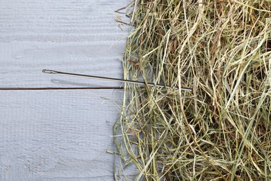 Sewing needle in haystack on grey wooden background, top view