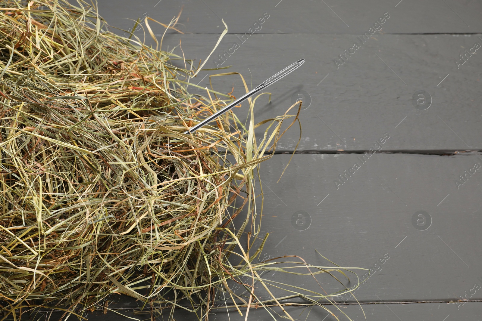 Image of Sewing needle in haystack on grey wooden background, top view