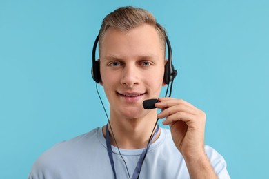 Photo of Technical support call center. Portrait of smiling operator on light blue background