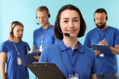 Photo of Technical support call center. Team of friendly operators working on light blue background