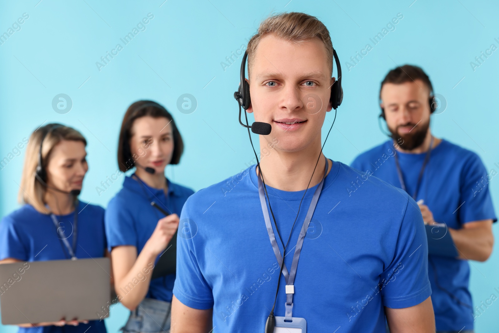 Photo of Technical support call center. Team of friendly operators working on light blue background