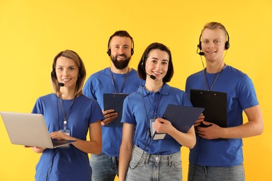 Technical support call center. Team of friendly operators on yellow background