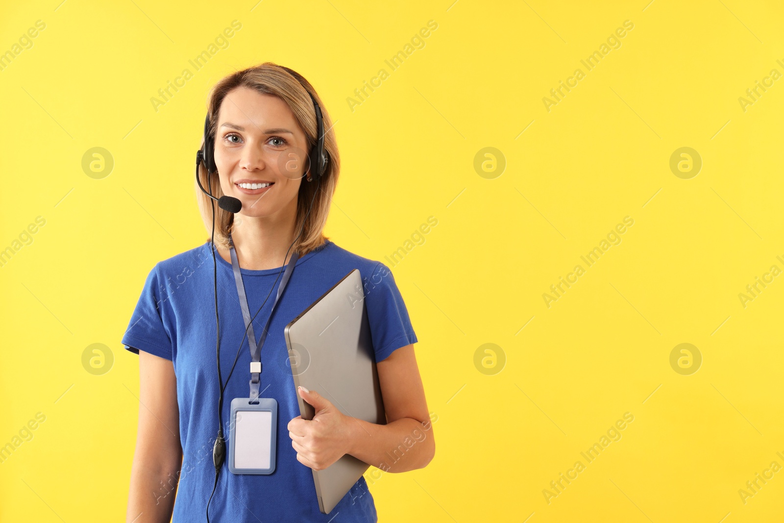 Photo of Technical support call center. Smiling operator with laptop on yellow background. Space for text