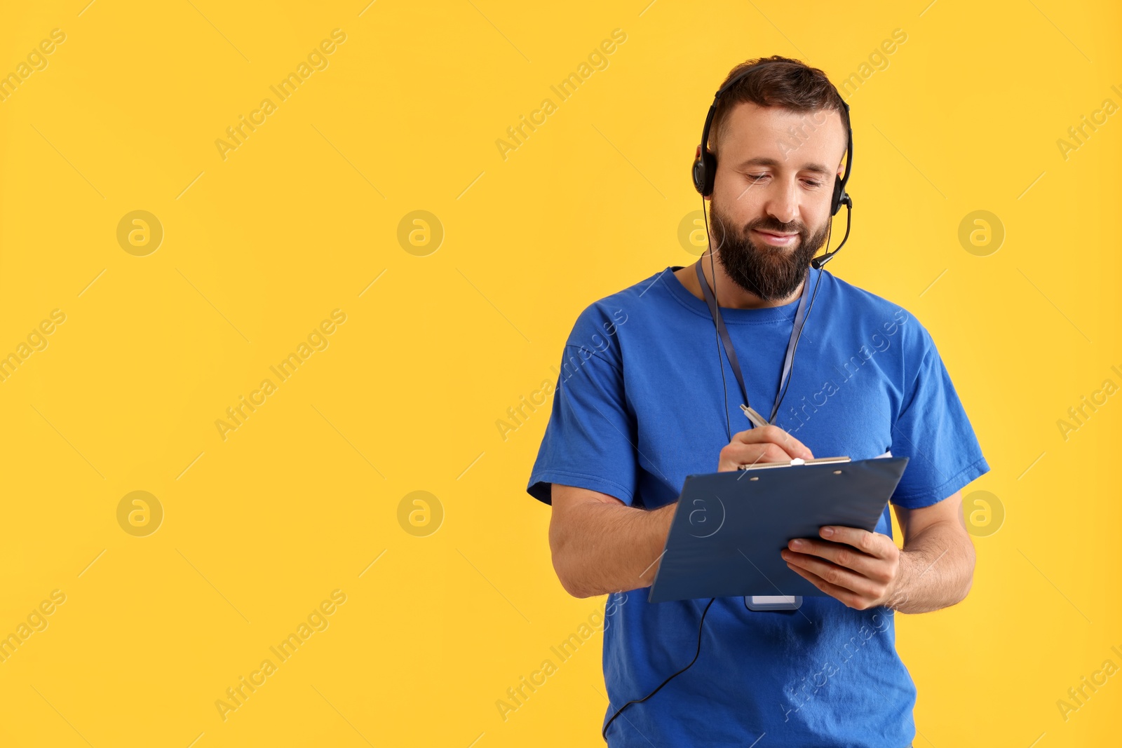 Photo of Technical support call center. Operator working with clipboard on yellow background. Space for text