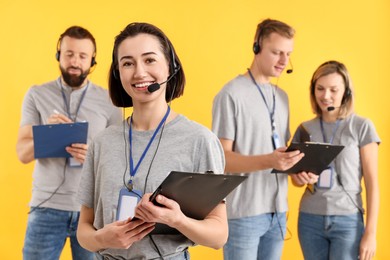 Photo of Technical support call center. Team of friendly operators on yellow background