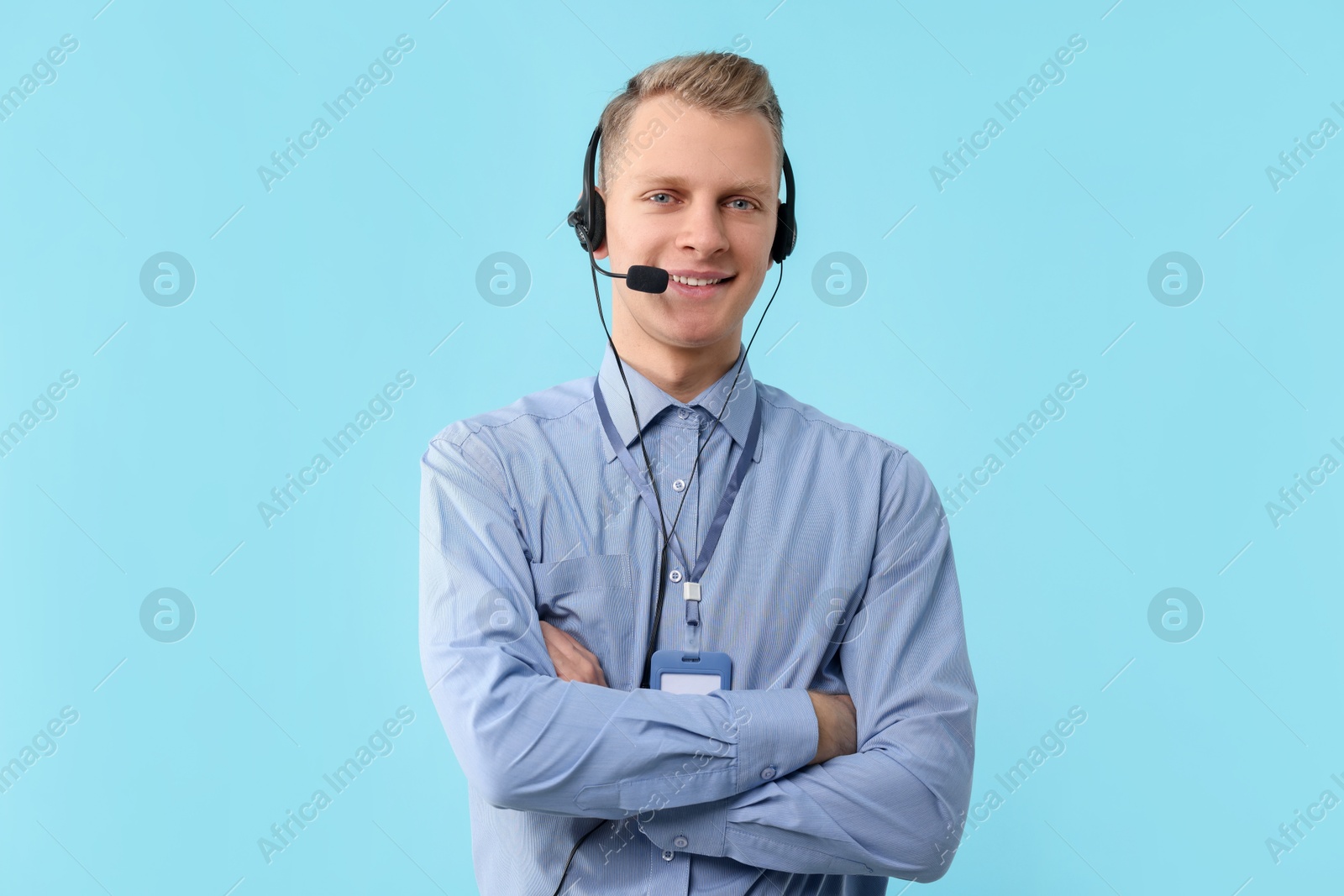 Photo of Technical support call center. Smiling operator with crossed arms on light blue background