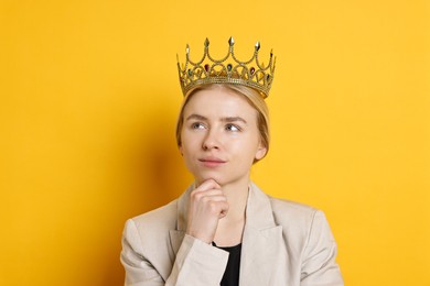 Photo of Thoughtful businesswoman in elegant crown on yellow background