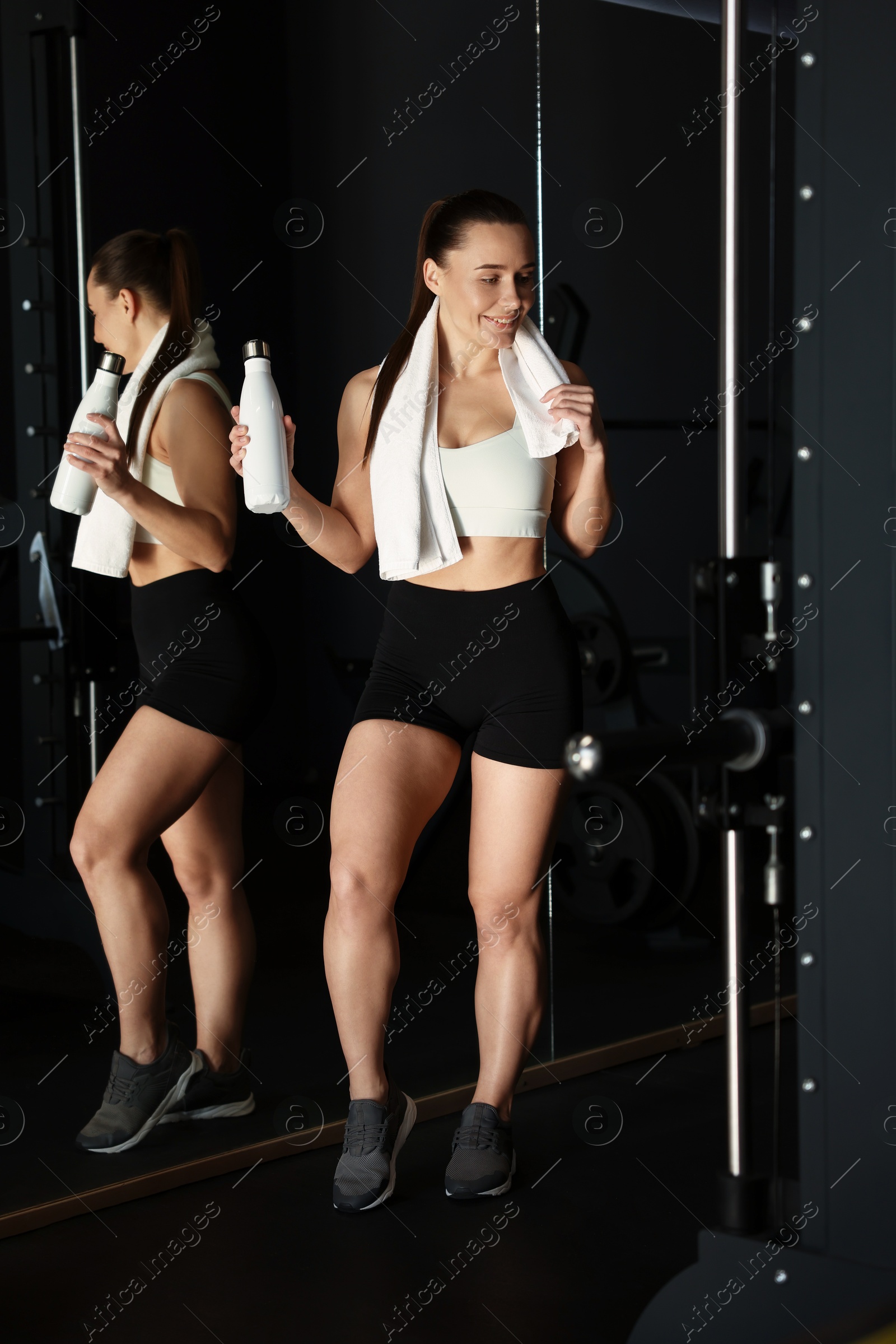 Photo of Happy woman with towel and water bottle in gym