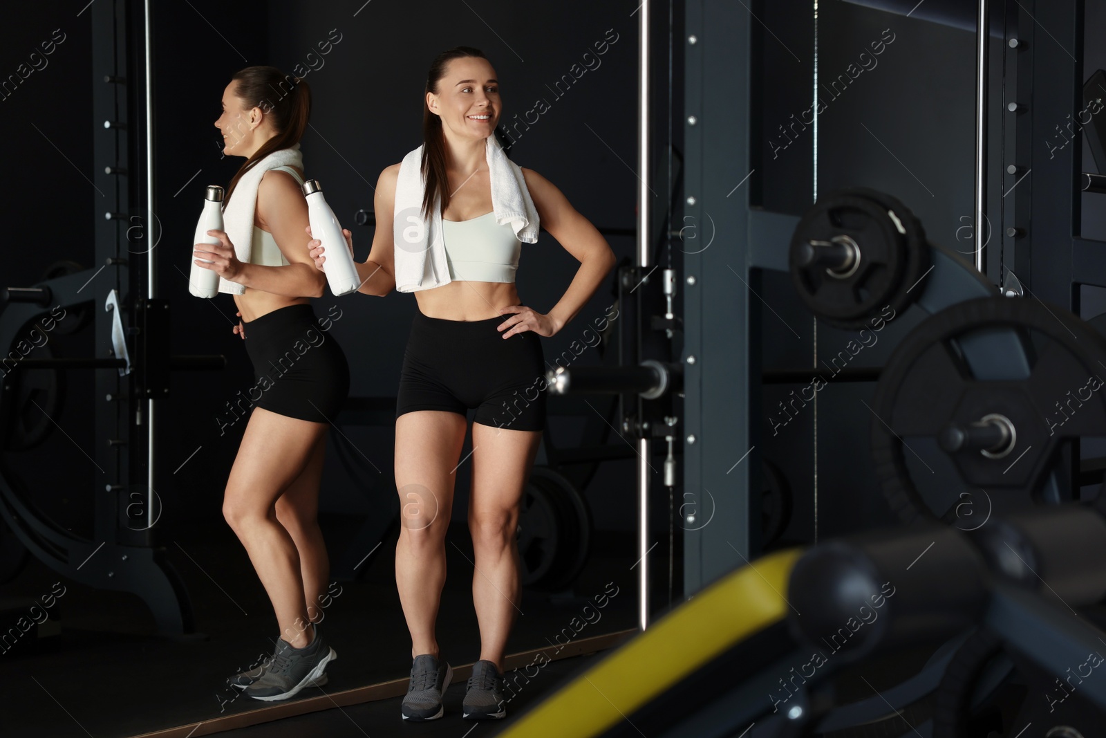 Photo of Happy woman with towel and water bottle in gym