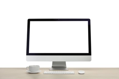 Photo of Computer monitor, keyboard, mouse and cup of drink on wooden desk against white background