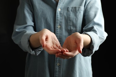 Woman holding something on black background, closeup