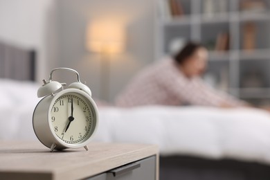 Young woman exercising on bed at home, focus on alarm clock. Morning routine