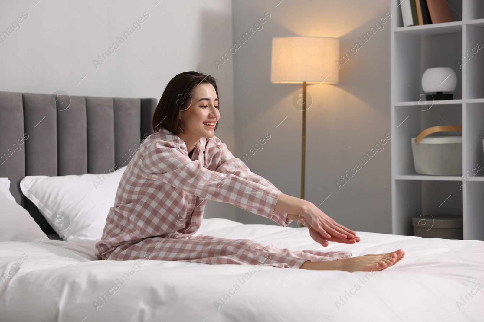 Photo of Young woman exercising on bed at home. Morning routine