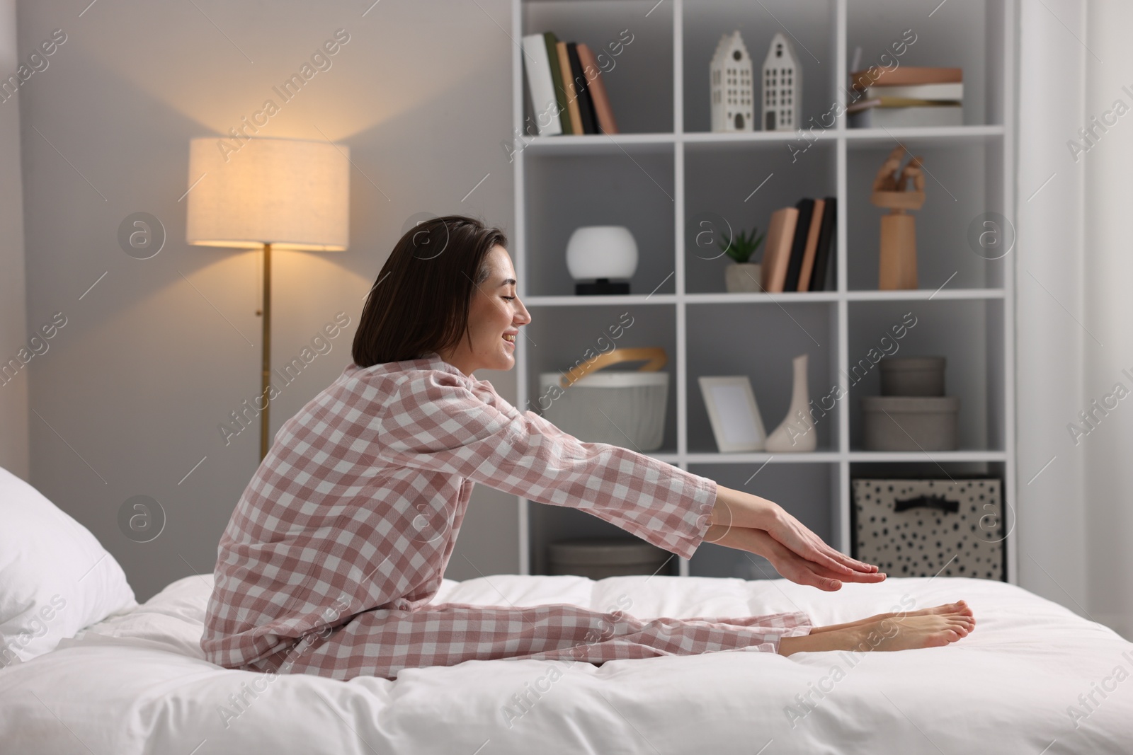 Photo of Young woman exercising on bed at home. Morning routine