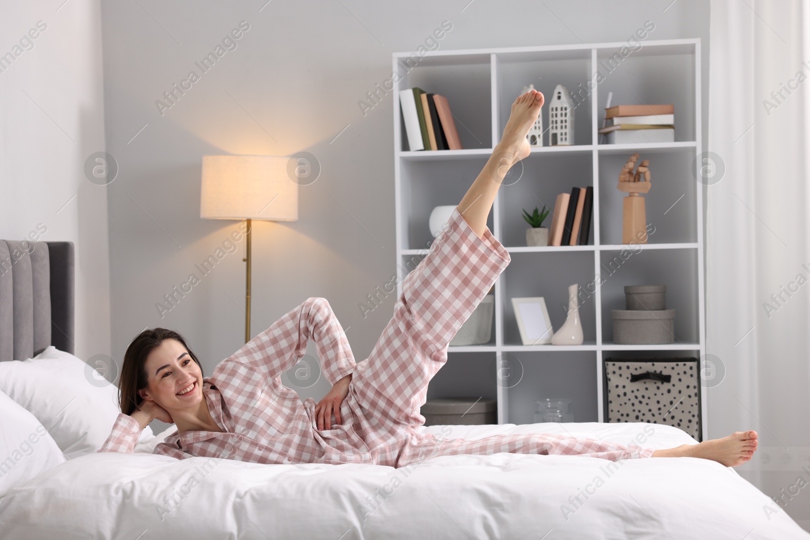 Photo of Young woman exercising on bed at home. Morning routine