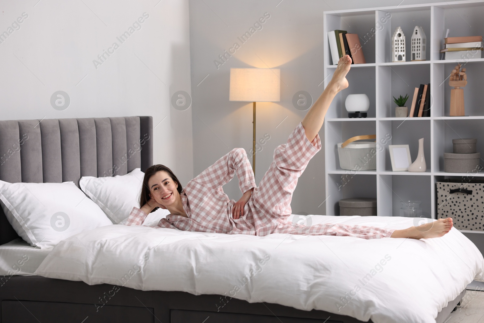 Photo of Young woman exercising on bed at home. Morning routine