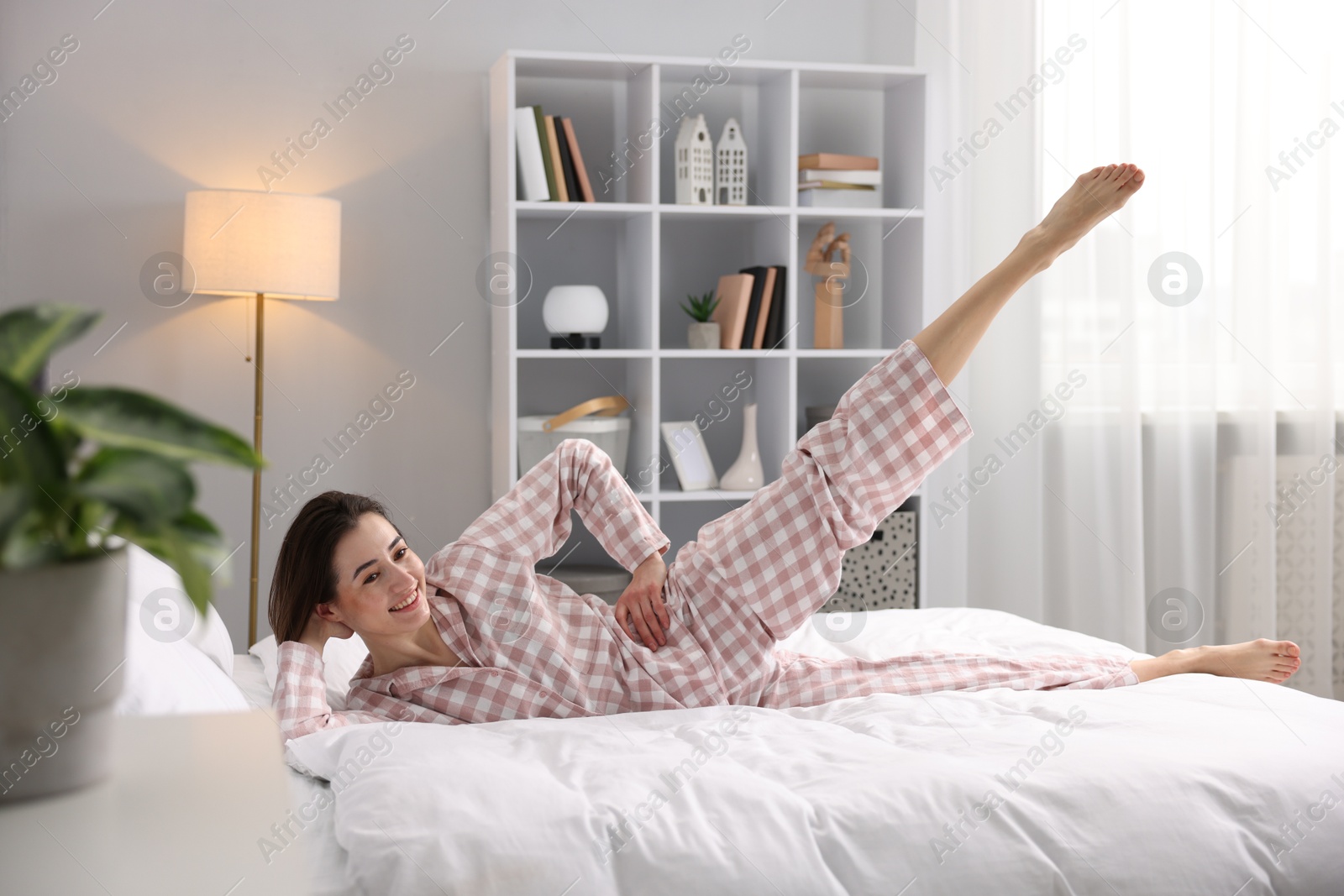 Photo of Young woman exercising on bed at home. Morning routine