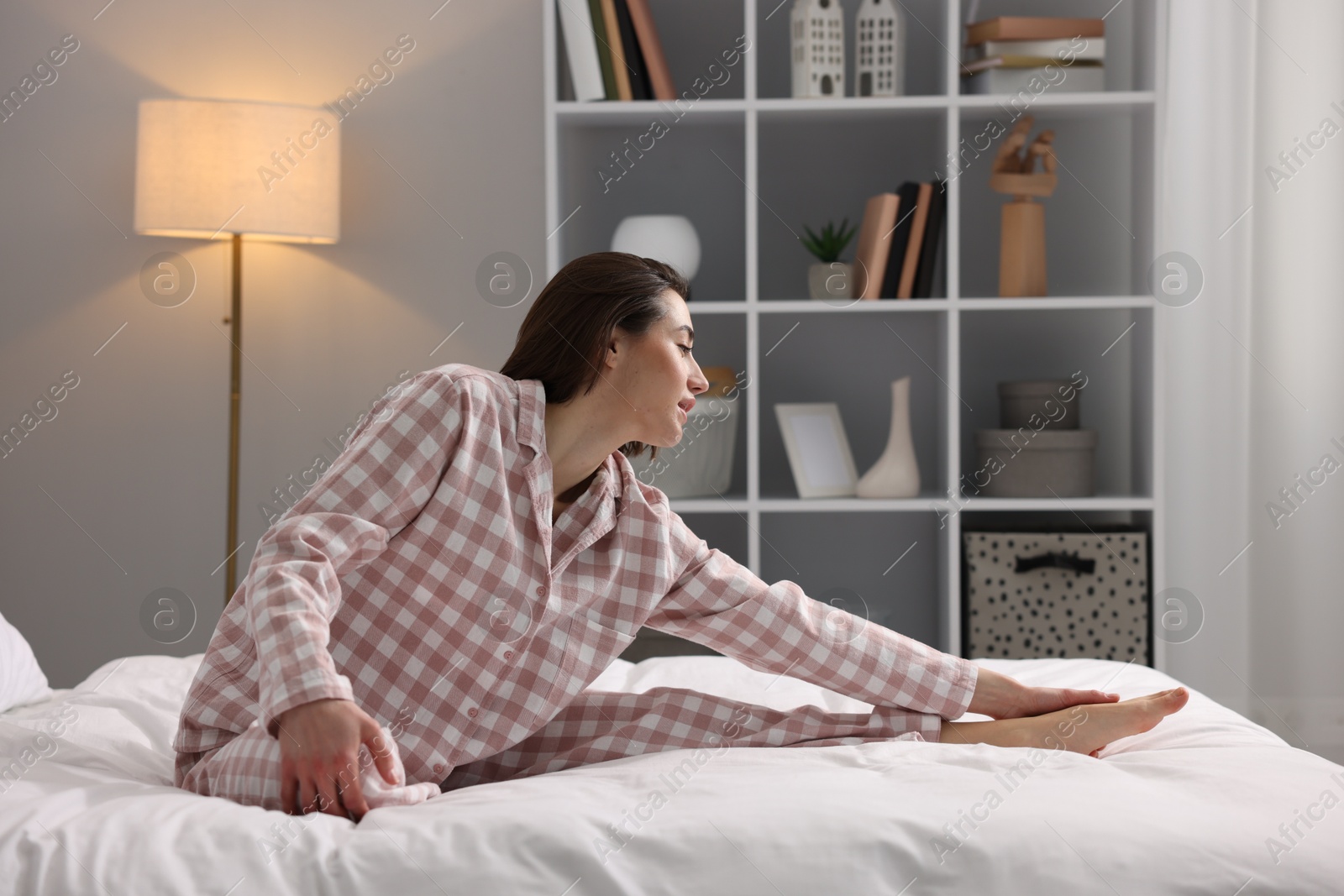 Photo of Young woman exercising on bed at home. Morning routine