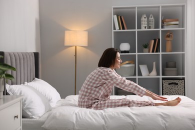 Young woman exercising on bed at home. Morning routine