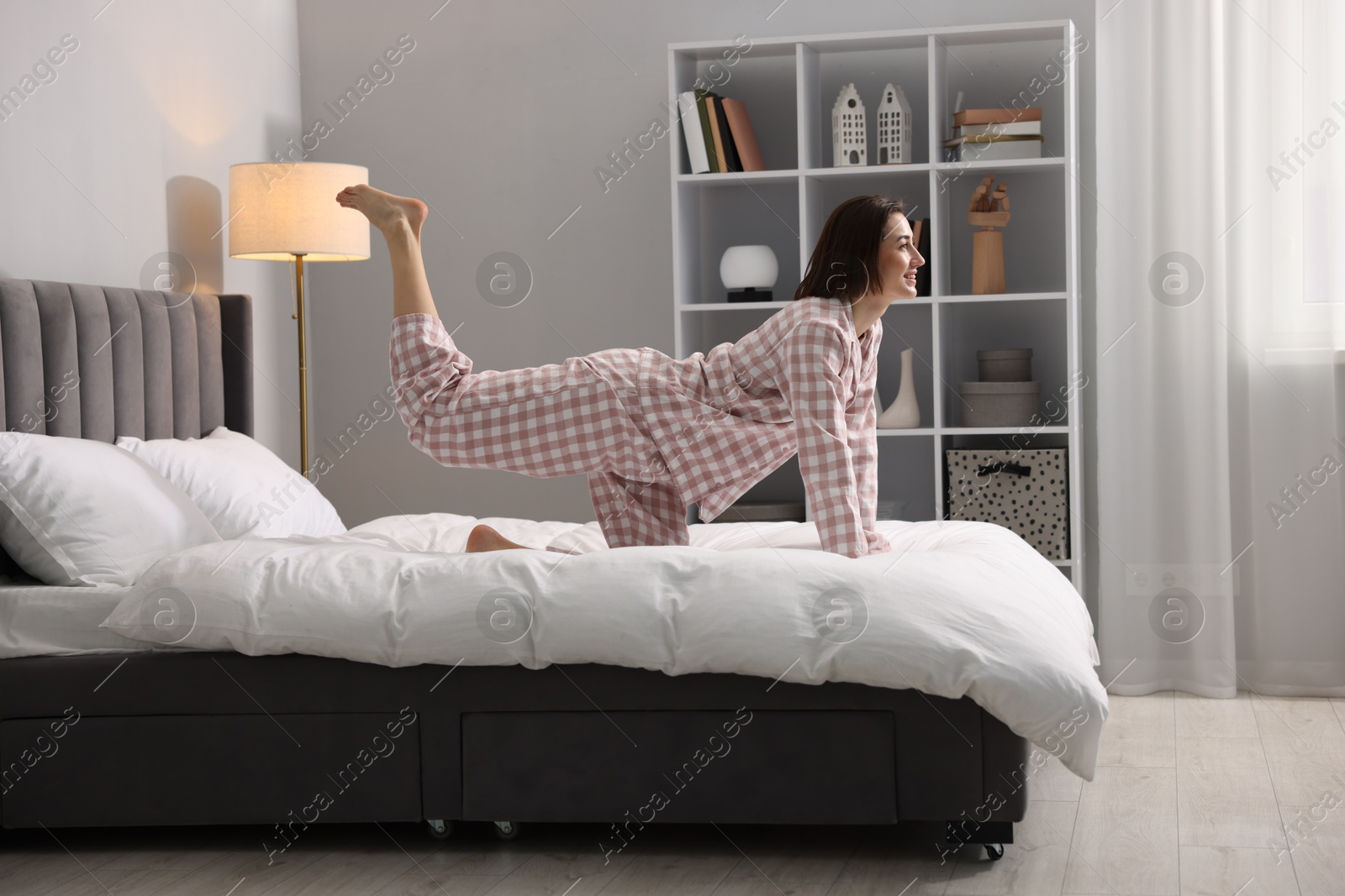 Photo of Young woman exercising on bed at home. Morning routine