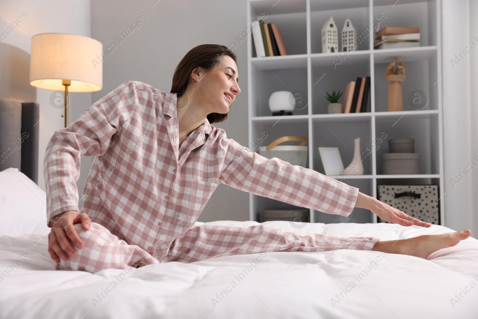 Photo of Young woman exercising on bed at home. Morning routine