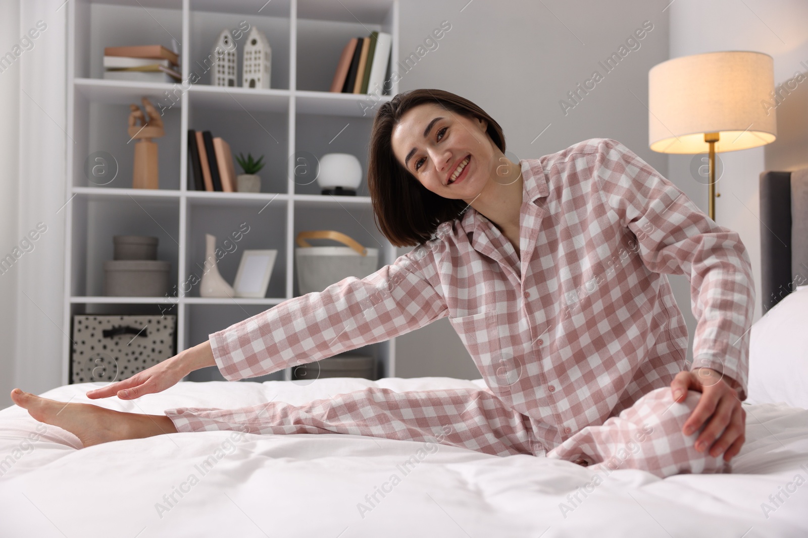 Photo of Young woman exercising on bed at home. Morning routine