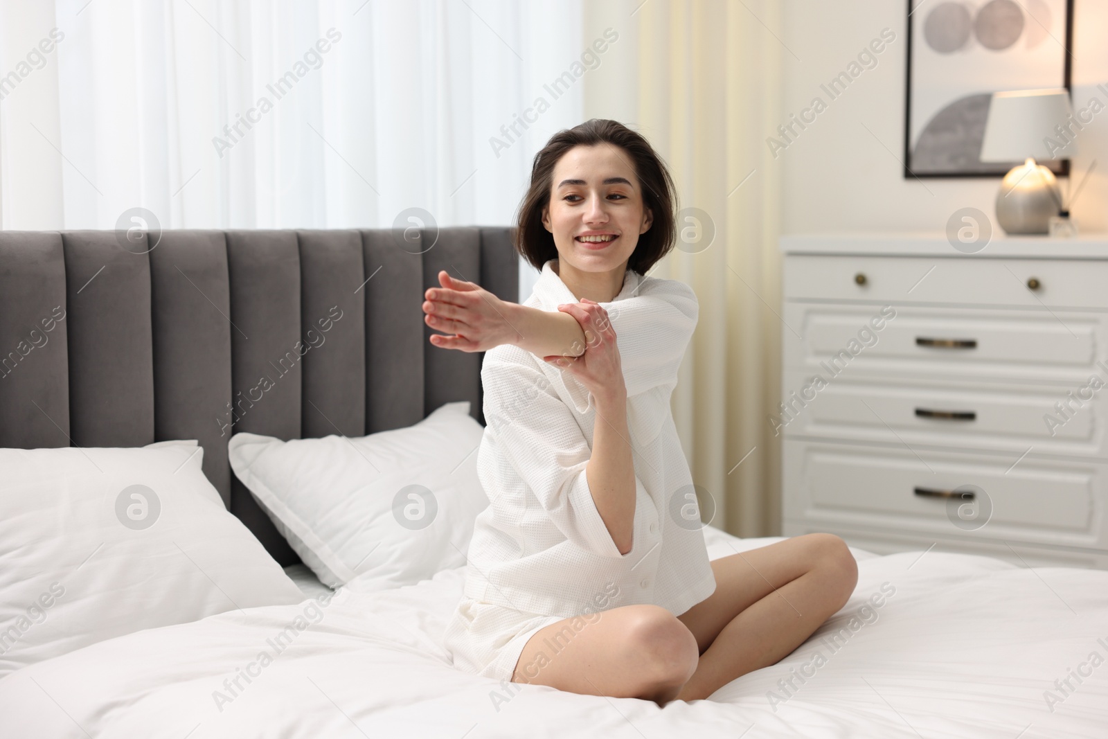 Photo of Young woman exercising on bed at home. Morning routine