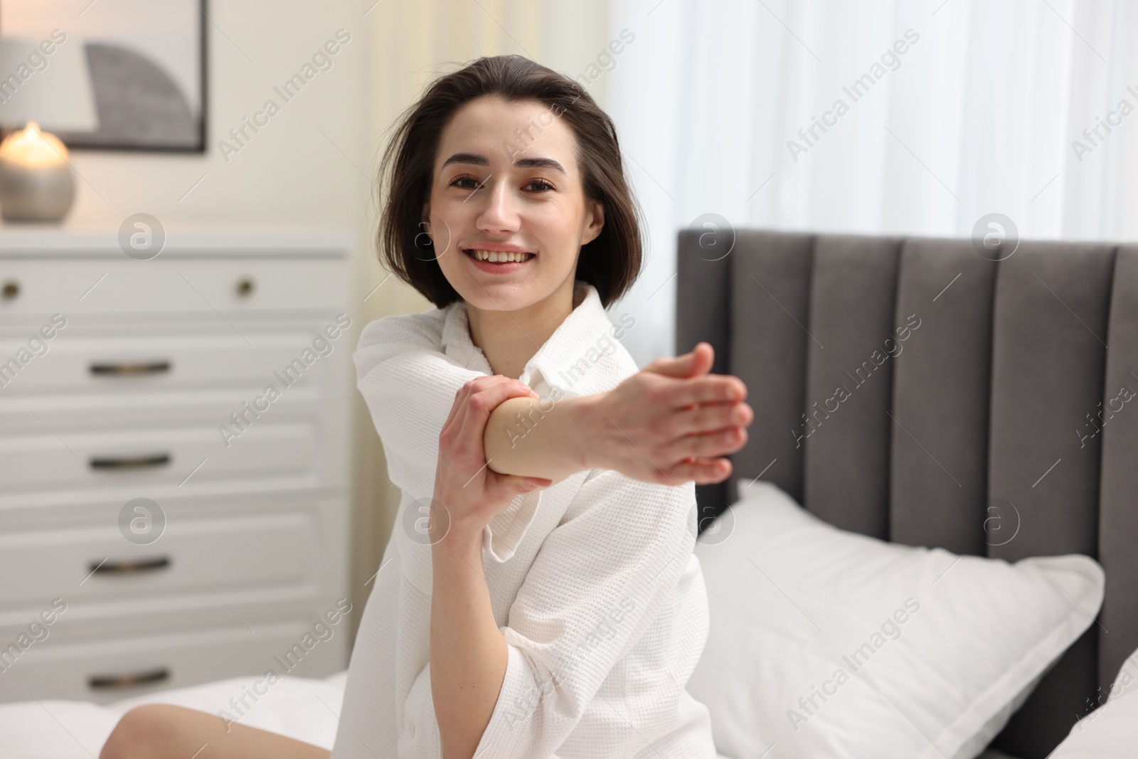 Photo of Young woman exercising on bed at home. Morning routine