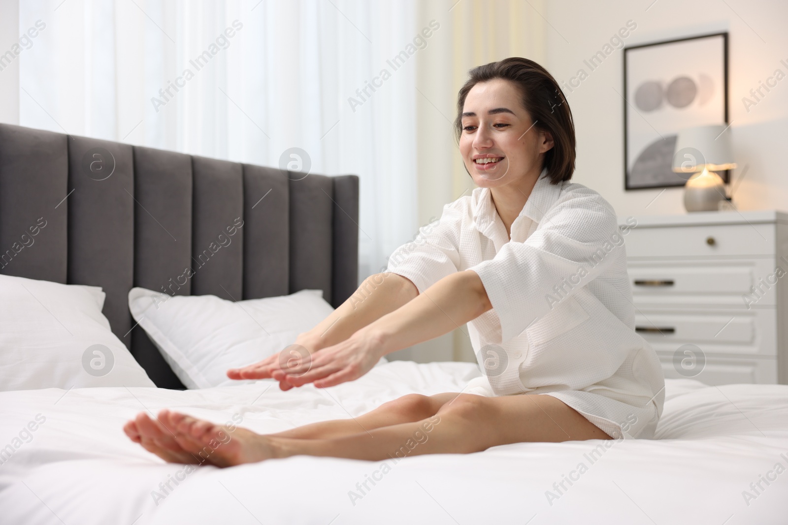 Photo of Young woman exercising on bed at home. Morning routine