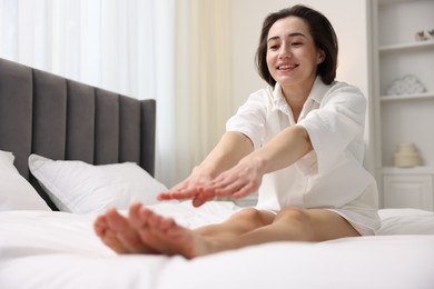 Photo of Young woman exercising on bed at home. Morning routine