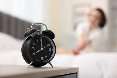 Photo of Young woman exercising on bed at home, focus on alarm clock. Morning routine