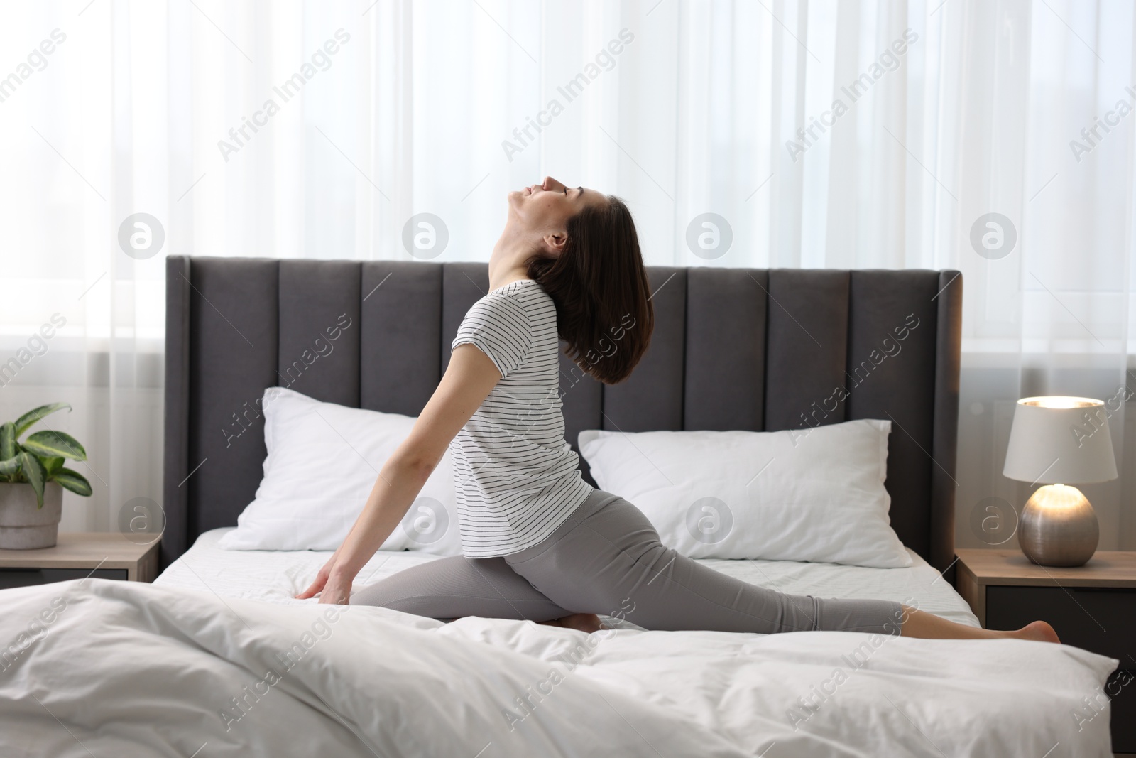 Photo of Young woman exercising on bed at home. Morning routine