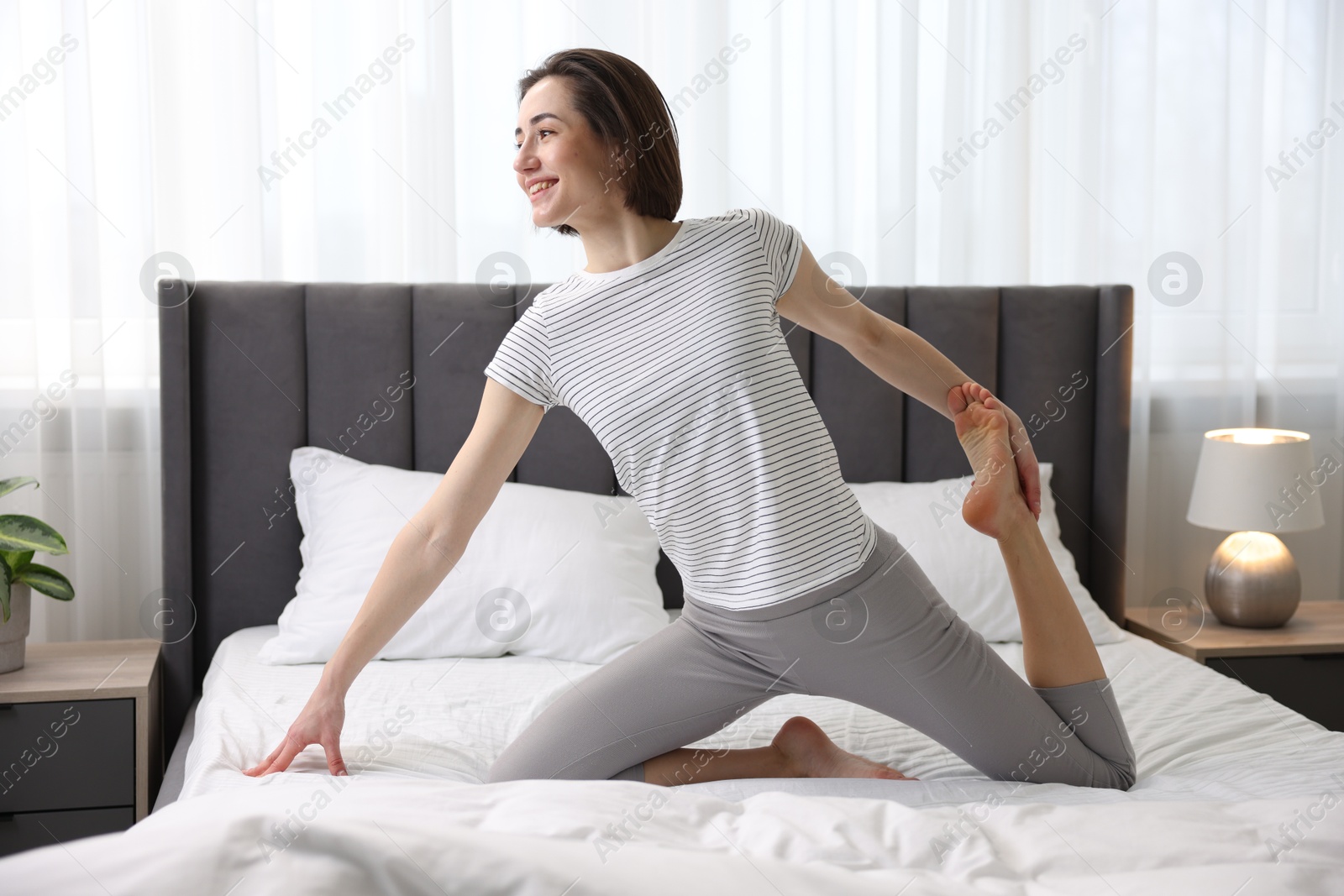 Photo of Young woman exercising on bed at home. Morning routine